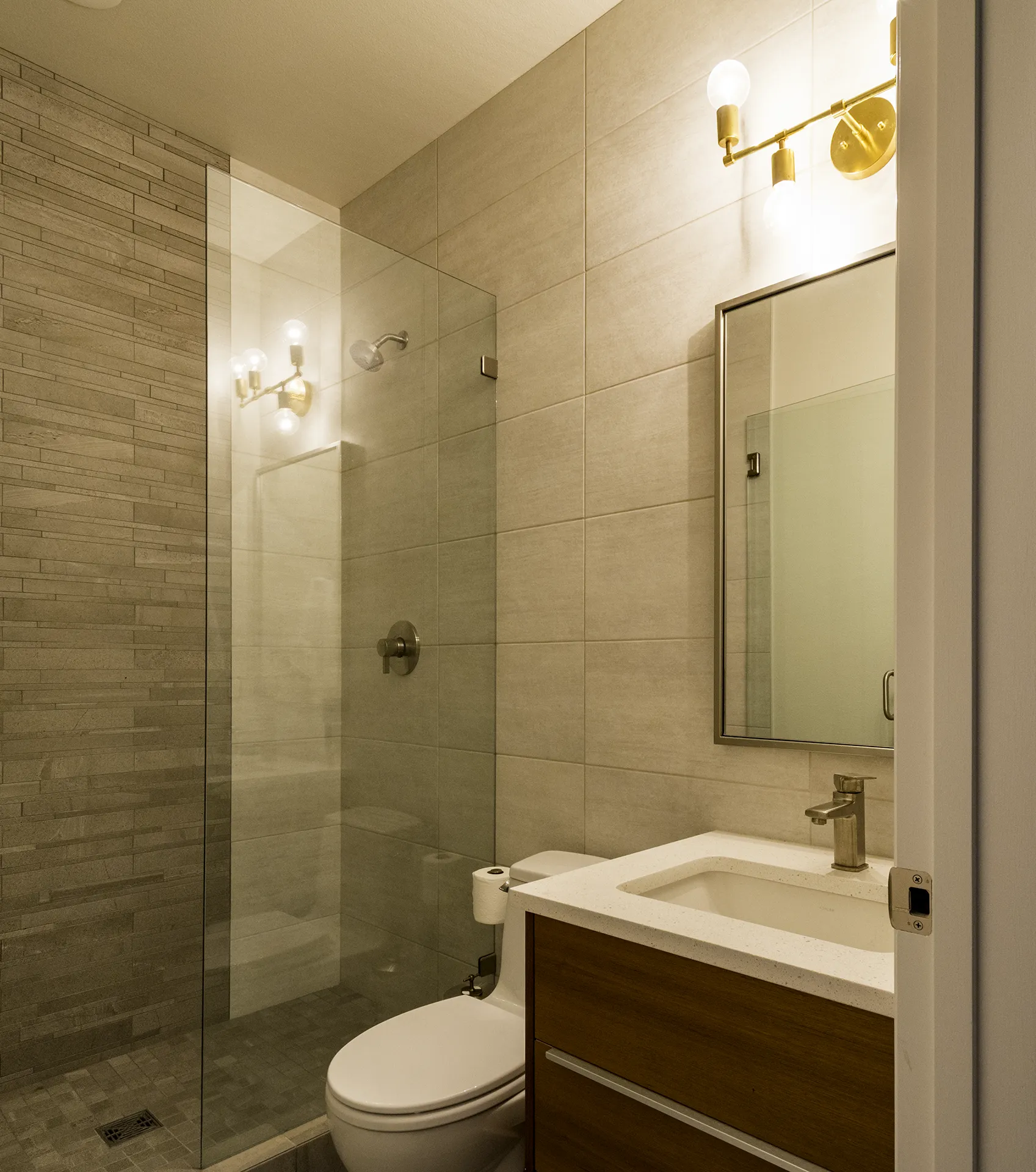 Issaquah bathroom remodel with tiled walk-in shower, glass panel, linear mosaic accent, and floating walnut vanity