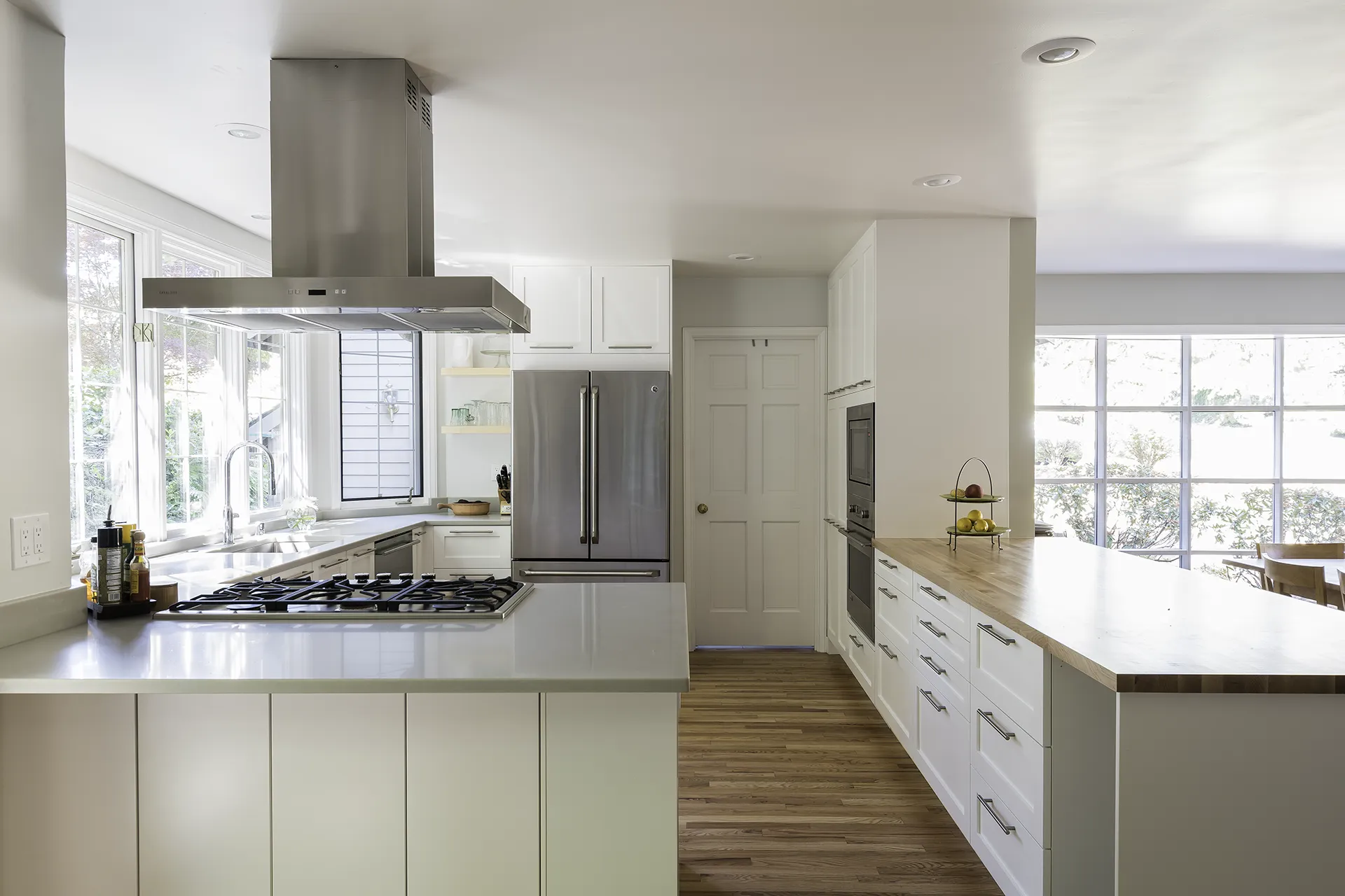 Issaquah kitchen remodel with white shaker cabinets, butcherblock and quartz countertops, island hood, and wall oven