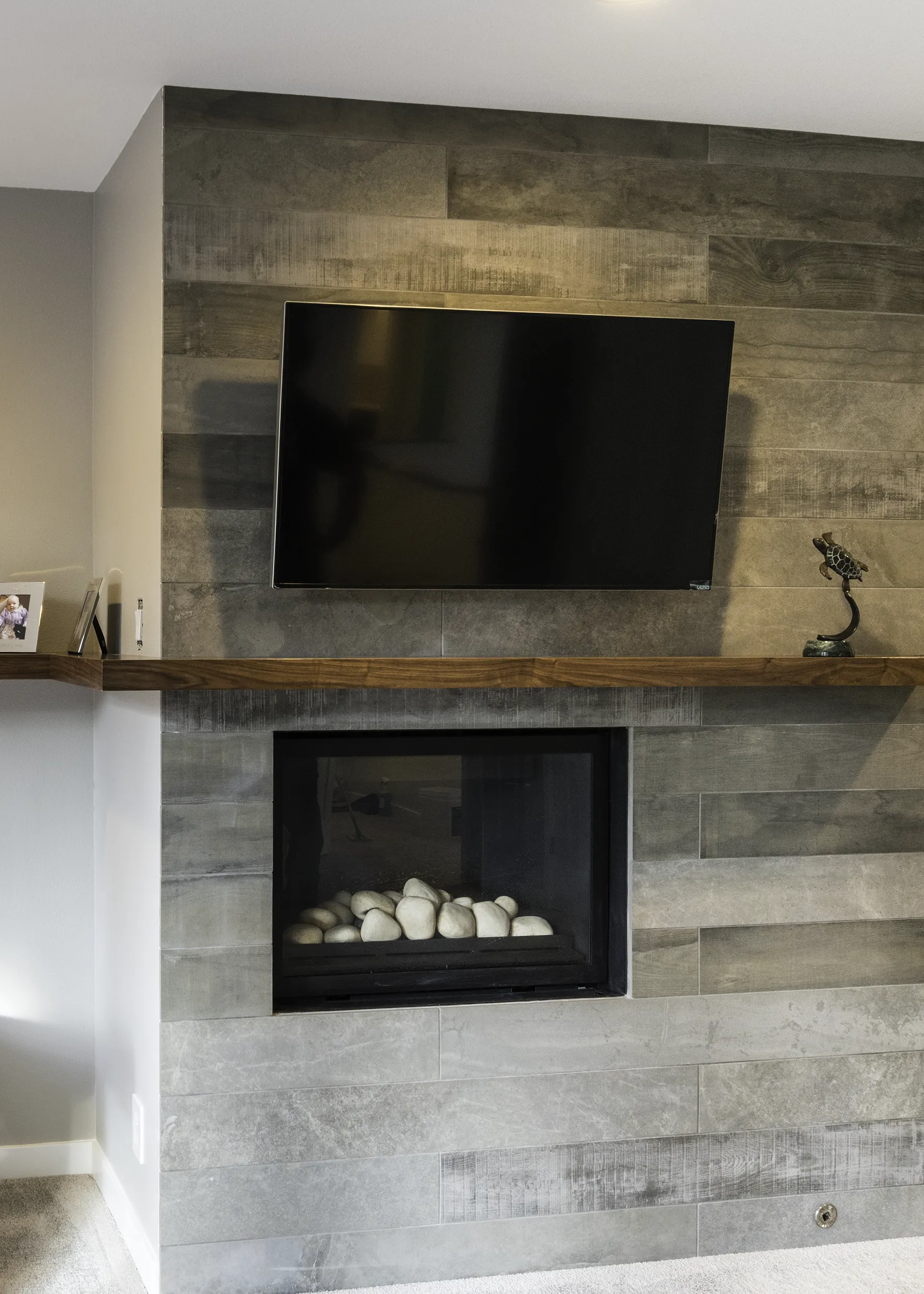 Close-up of walnut mantel and weathered plank tile around the primary bedroom fireplace