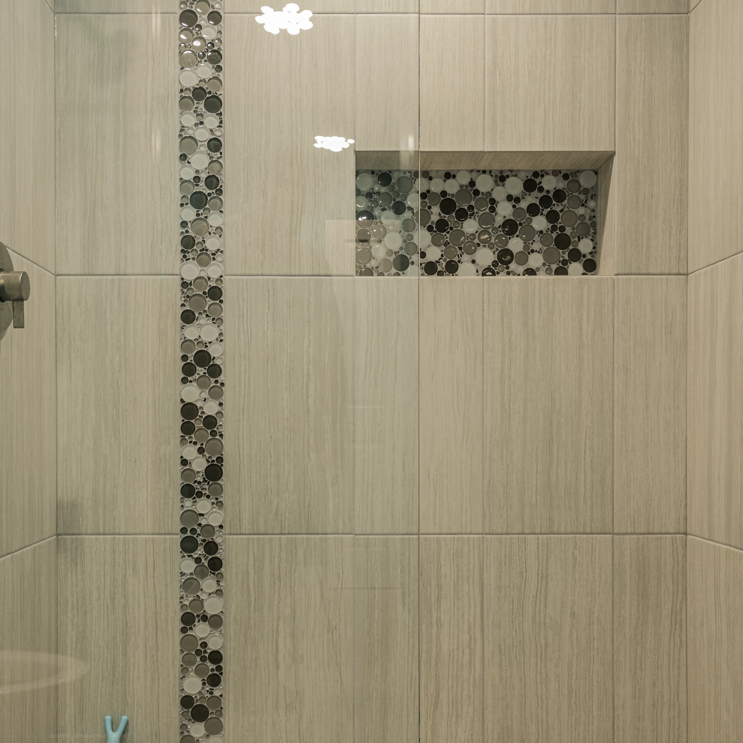Detail of bubble mosaic accent strip and matching niche in kids bathroom shower