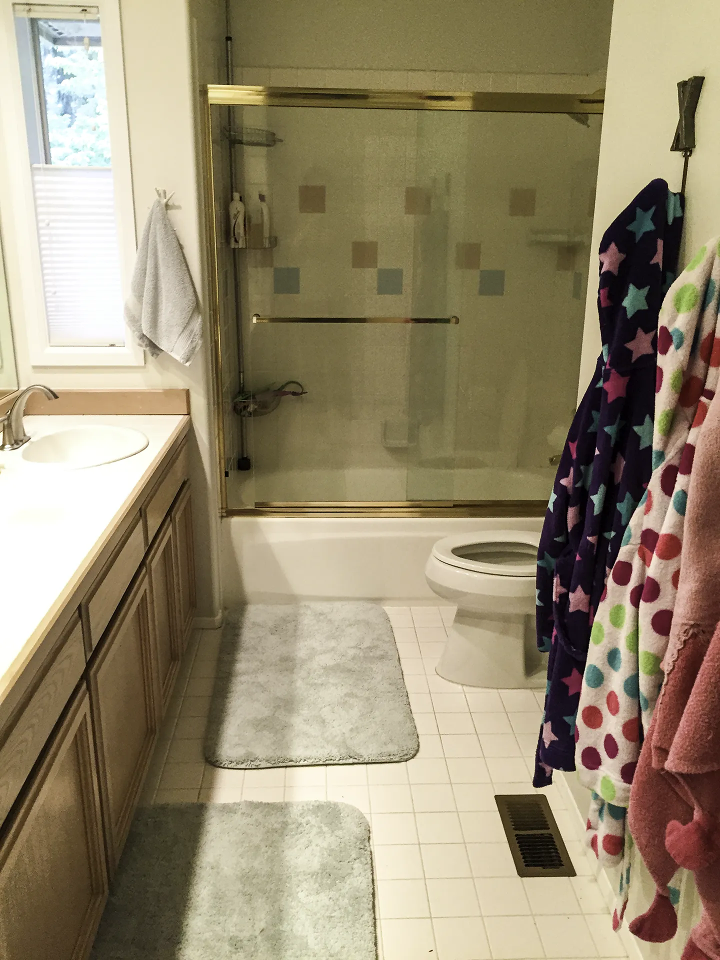 Kids bathroom before remodel with brass shower doors and tub-shower combo