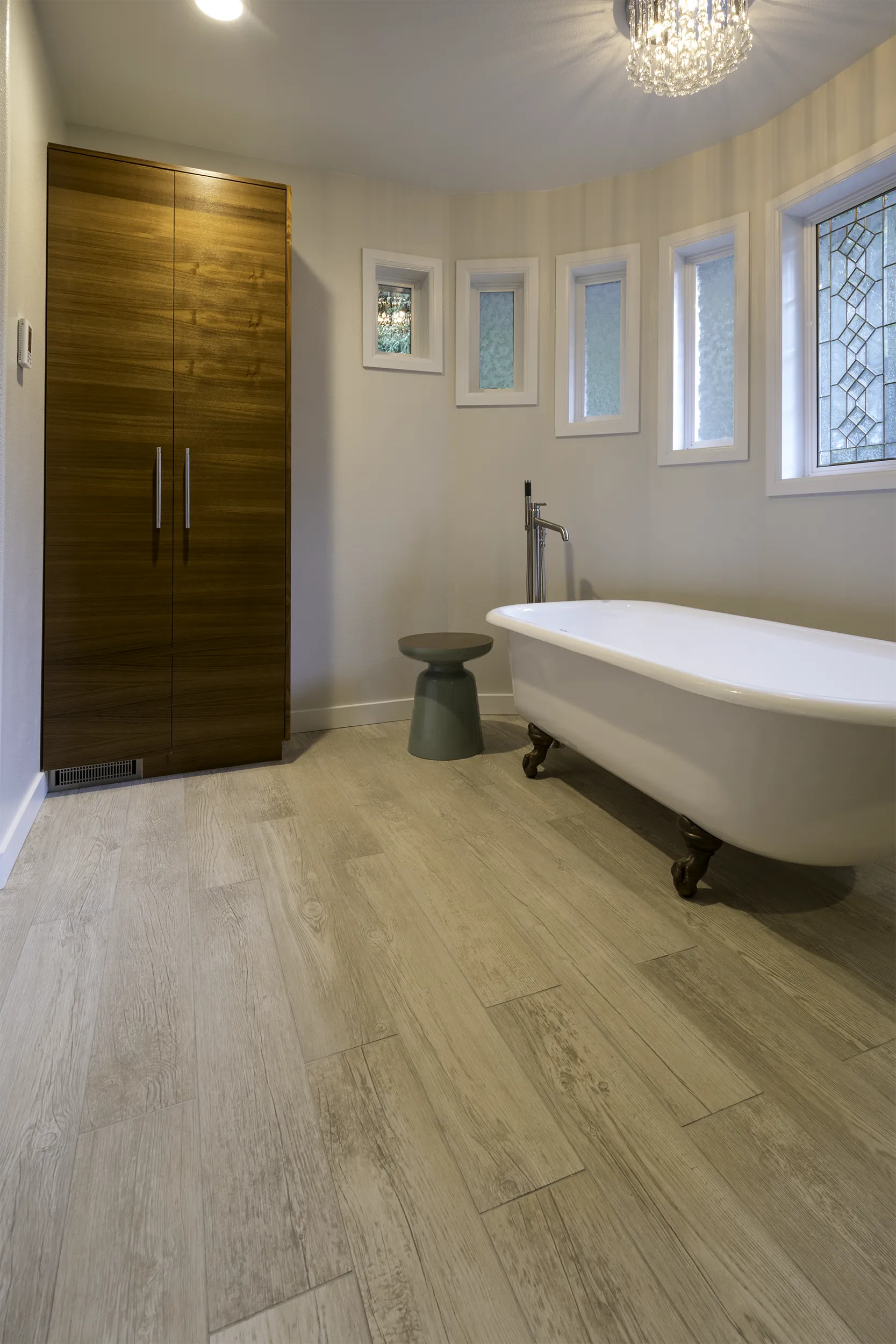 Primary bath with clawfoot soaking tub, crystal chandelier, and IKEA pantry cabinet with custom teak doors