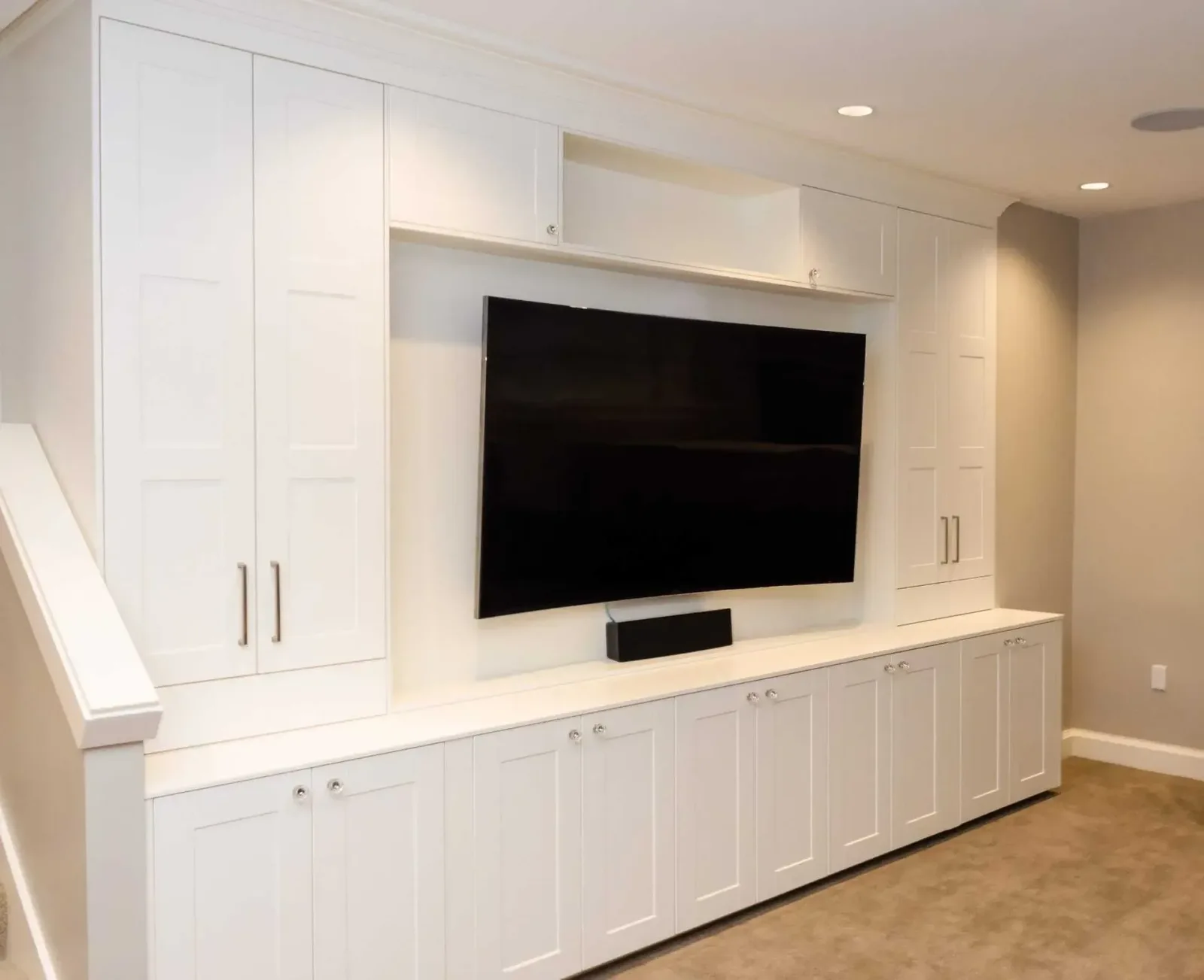 Basement media room with a built-in entertainment center in white shaker cabinets