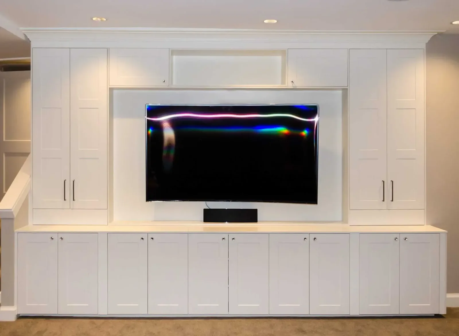 Basement play room built-in media wall with storage cabinets and crown molding