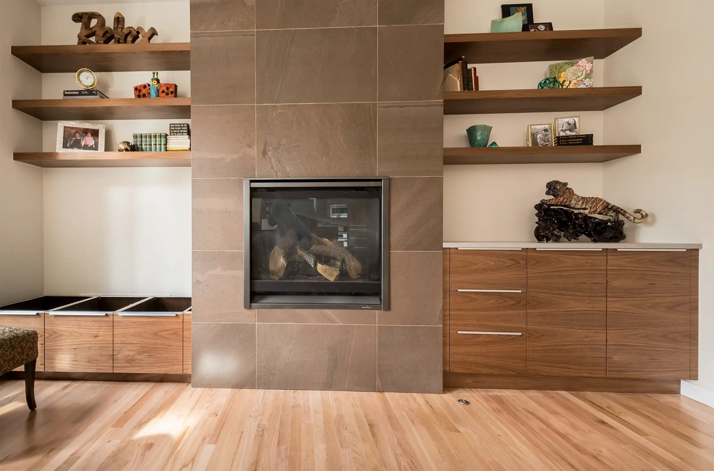 Built-ins around a fireplace with walnut floating shelves on one side and a drawer cabinet on the other