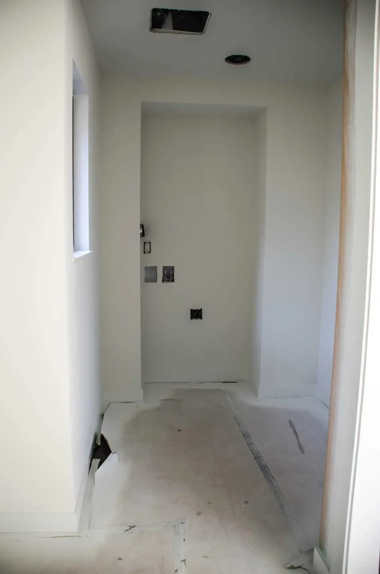 Laundry room before the remodel, a bare alcove with washer and dryer hookups and a dryer vent