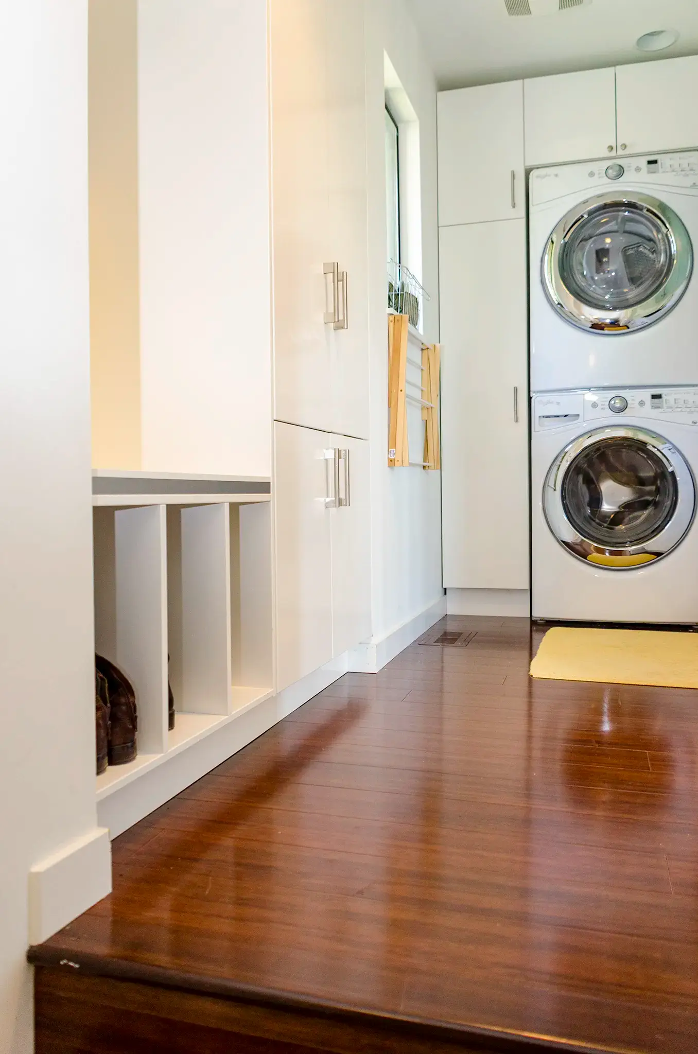 Laundry room cabinets running floor to ceiling beside a mudroom bench with boot cubbies