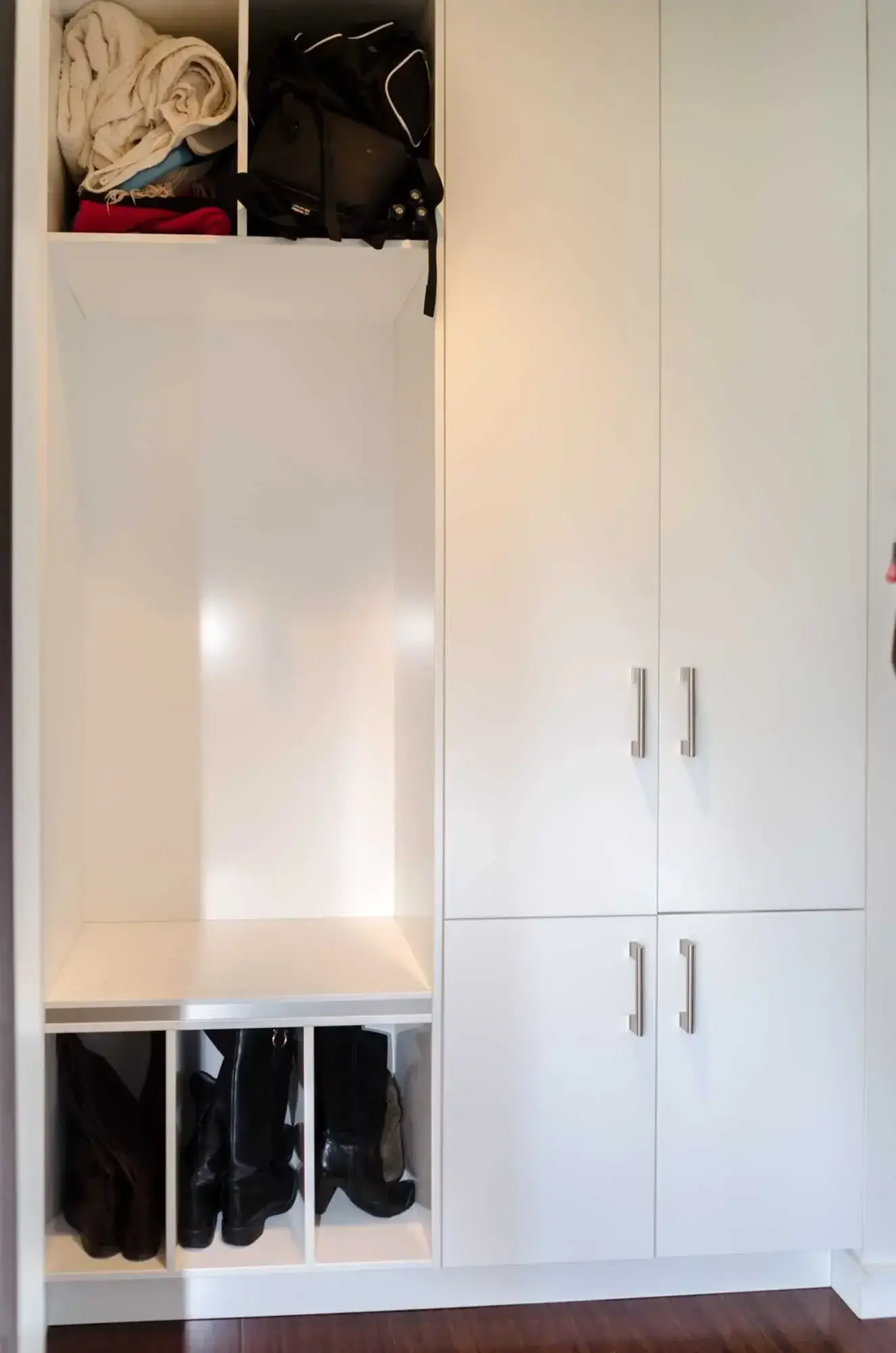 Mudroom bench with boot cubbies underneath and floor-to-ceiling storage cabinets alongside