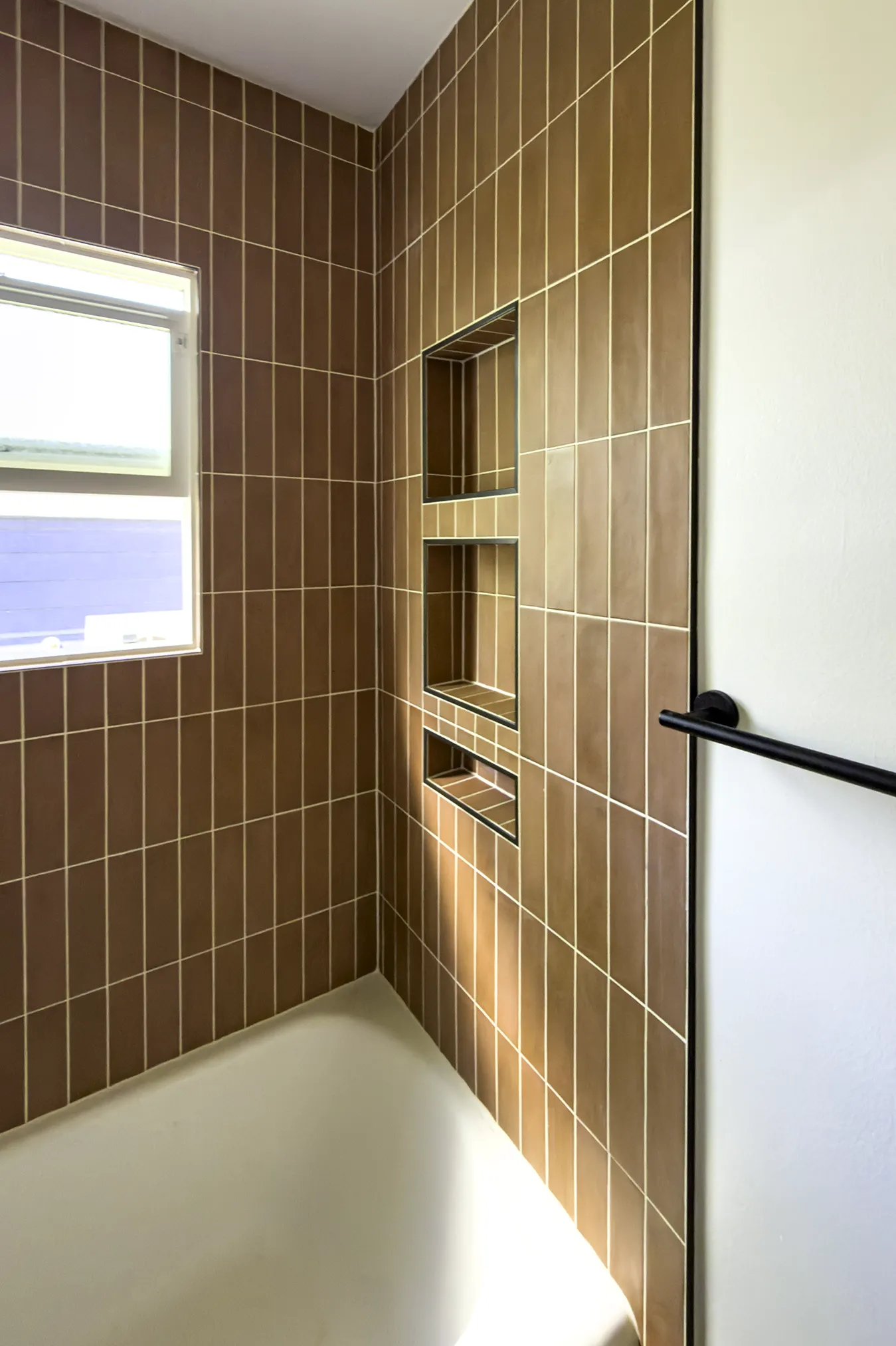 Tiled shower niches with matte black trim in a West Seattle bathroom remodel