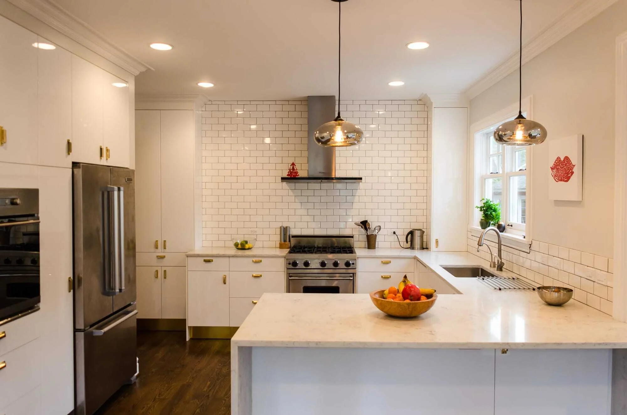 Completed IKEA kitchen with subway tile backsplash, pendant lights, and marble countertop