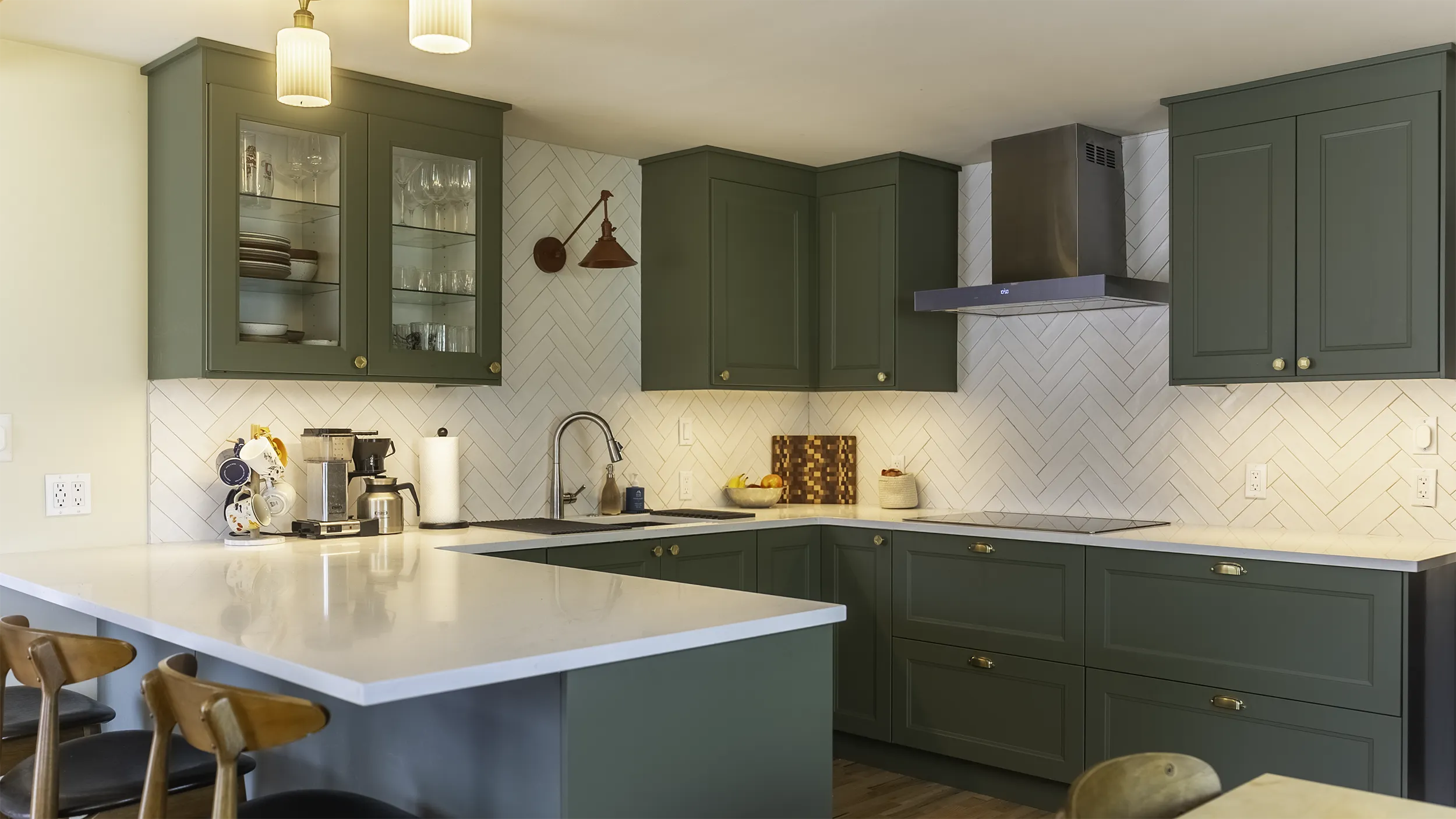 Sage green IKEA AXSTAD kitchen with brushed brass hardware, herringbone subway tile backsplash, and quartz peninsula in West Seattle
