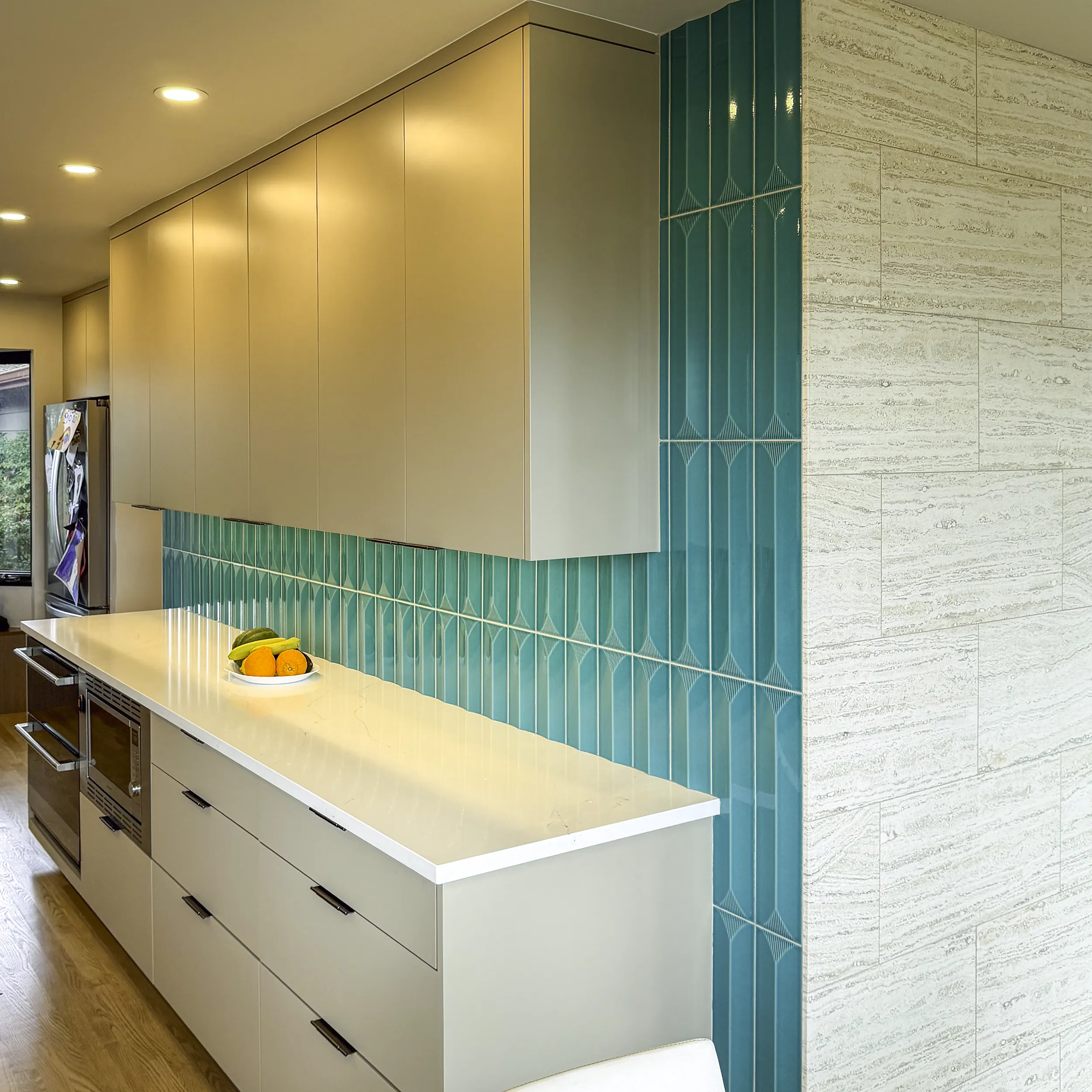 Vertical stacked teal green tile backsplash with travertine accent wall in a Seattle kitchen remodel