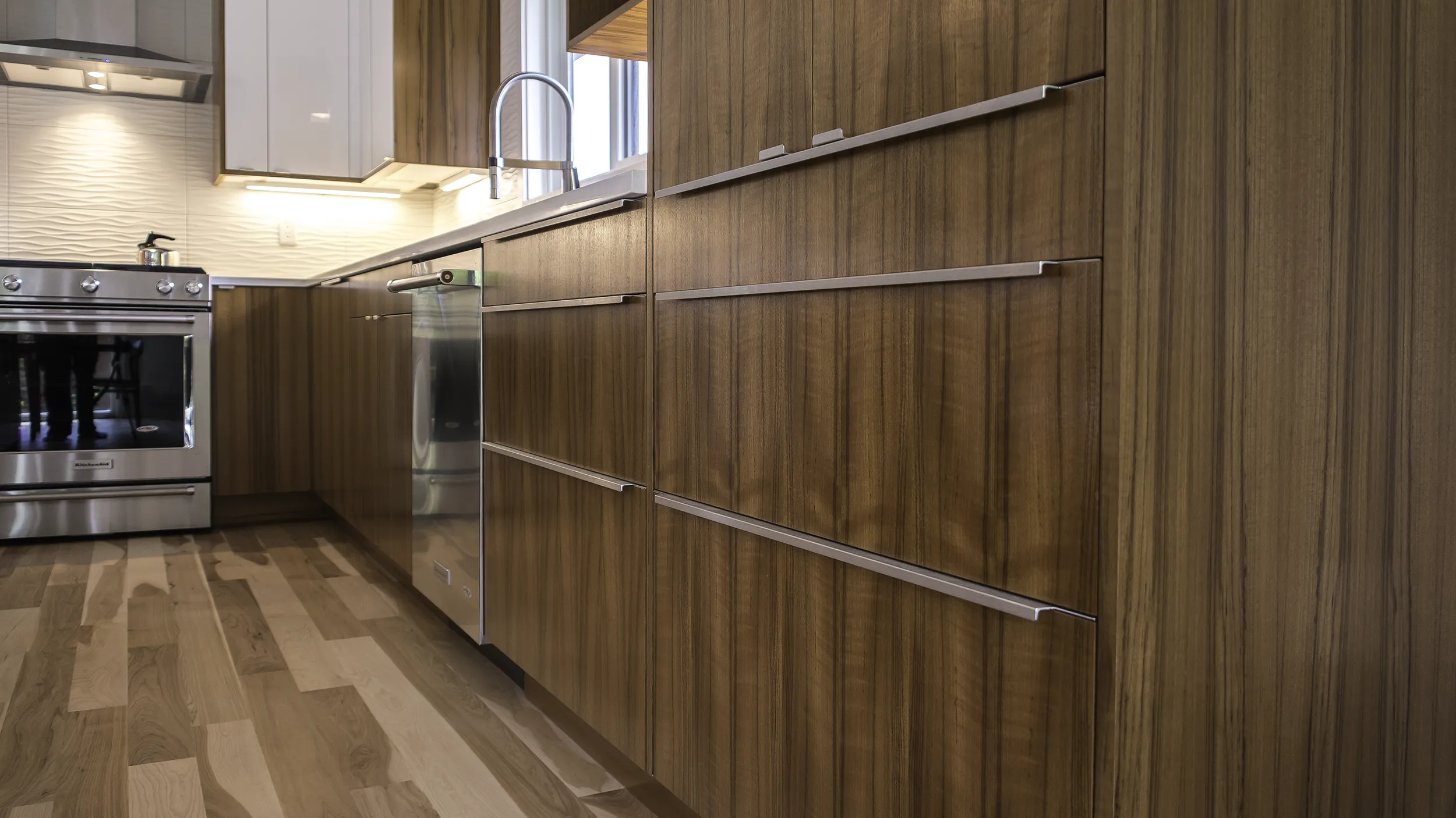 Custom walnut slab doors on IKEA SEKTION cabinet boxes with long aluminum pulls in Seattle kitchen remodel