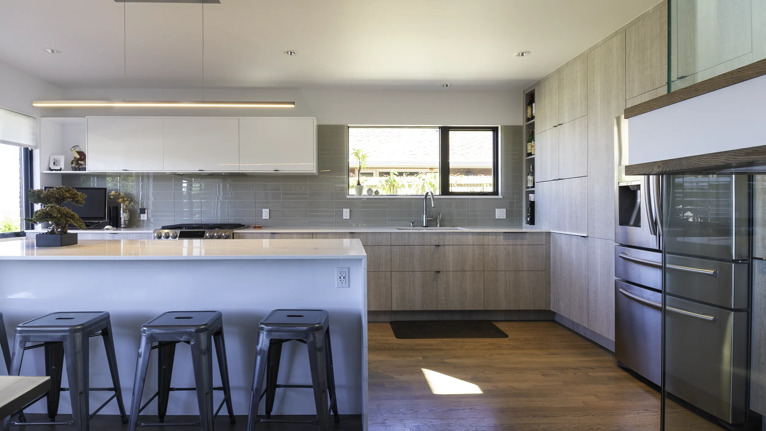 Modern IKEA SEKTION kitchen remodel with wood-tone cabinets, quartz waterfall island, and glass backsplash in Seattle