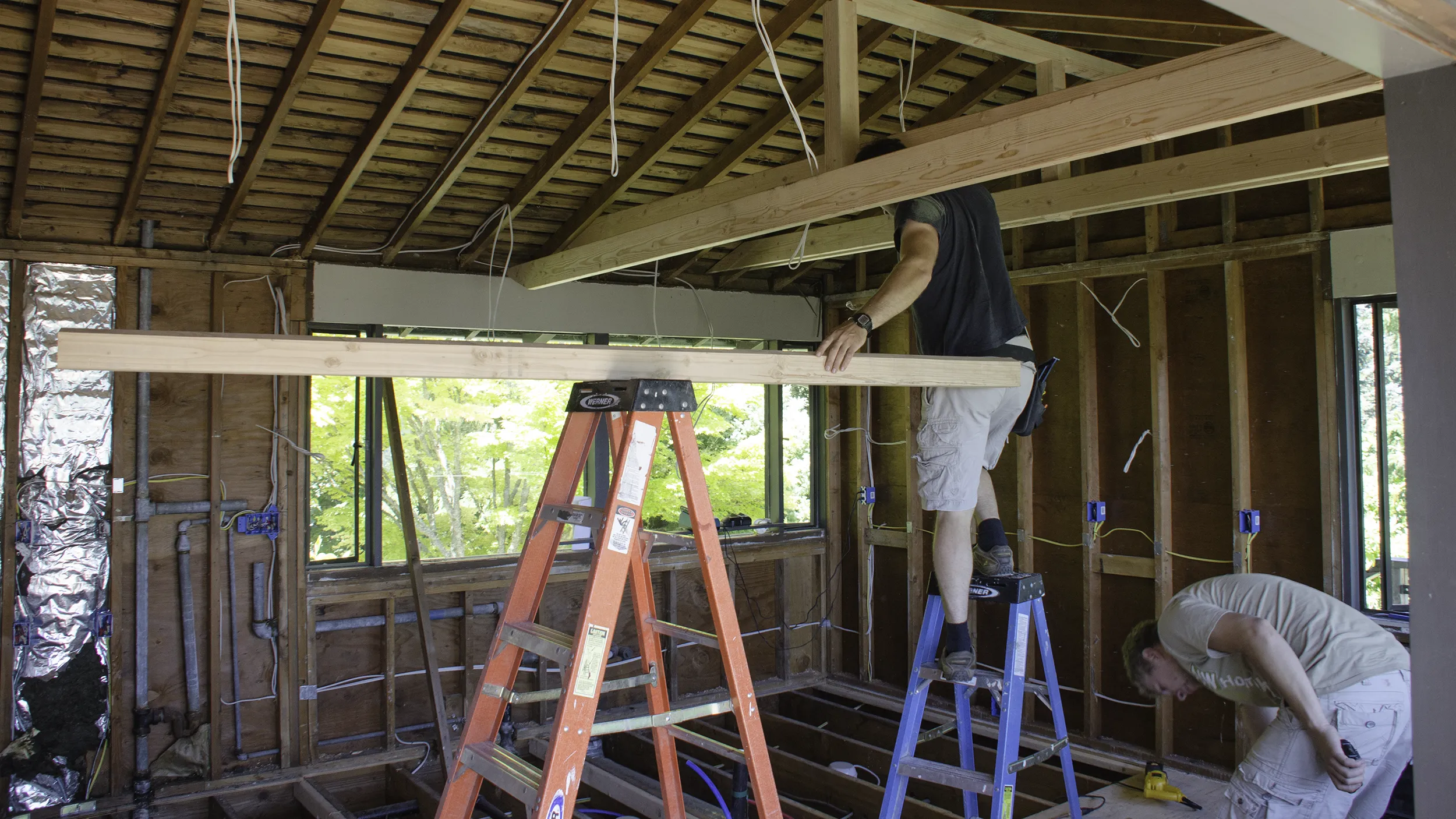 Kitchen remodel in progress showing exposed framing and crew members working on structural framing in Seattle home