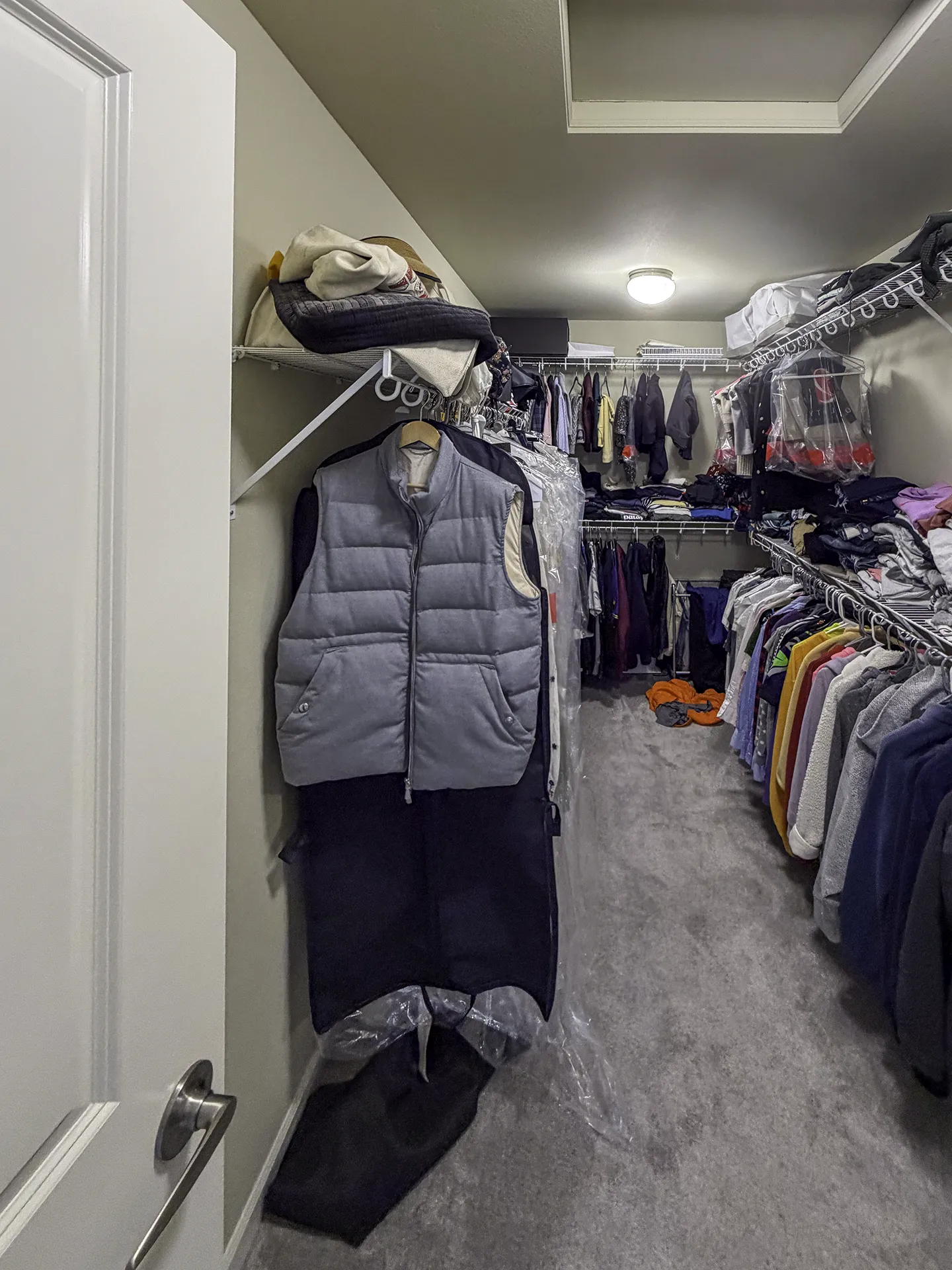 Before photo of cluttered master closet with basic wire shelving