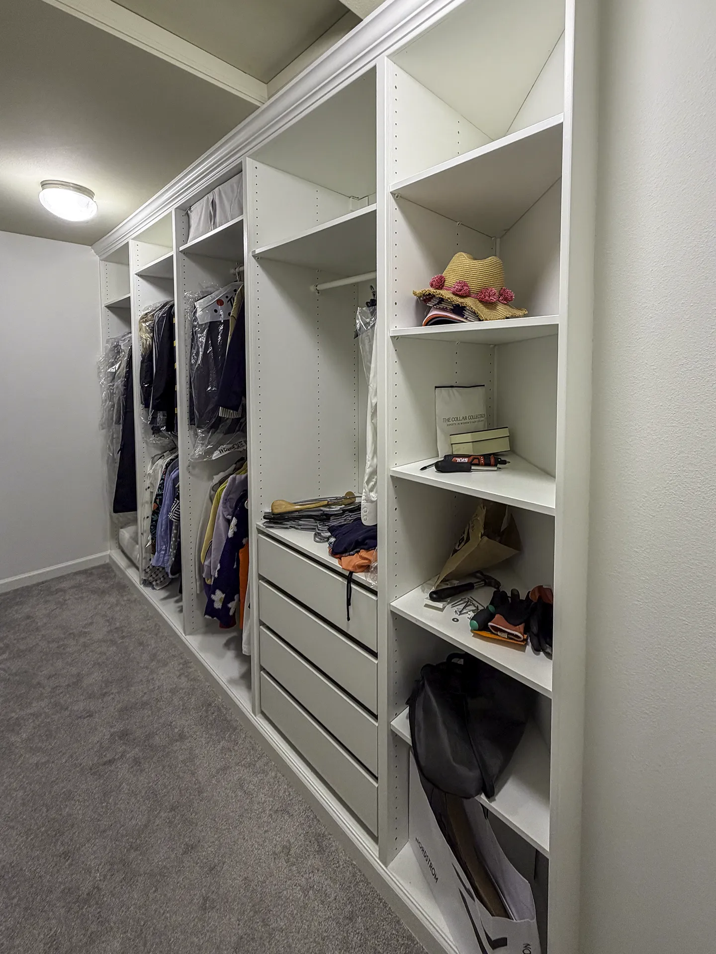 Finished IKEA PAX walk-in closet showing custom angled shelving and crown molding
