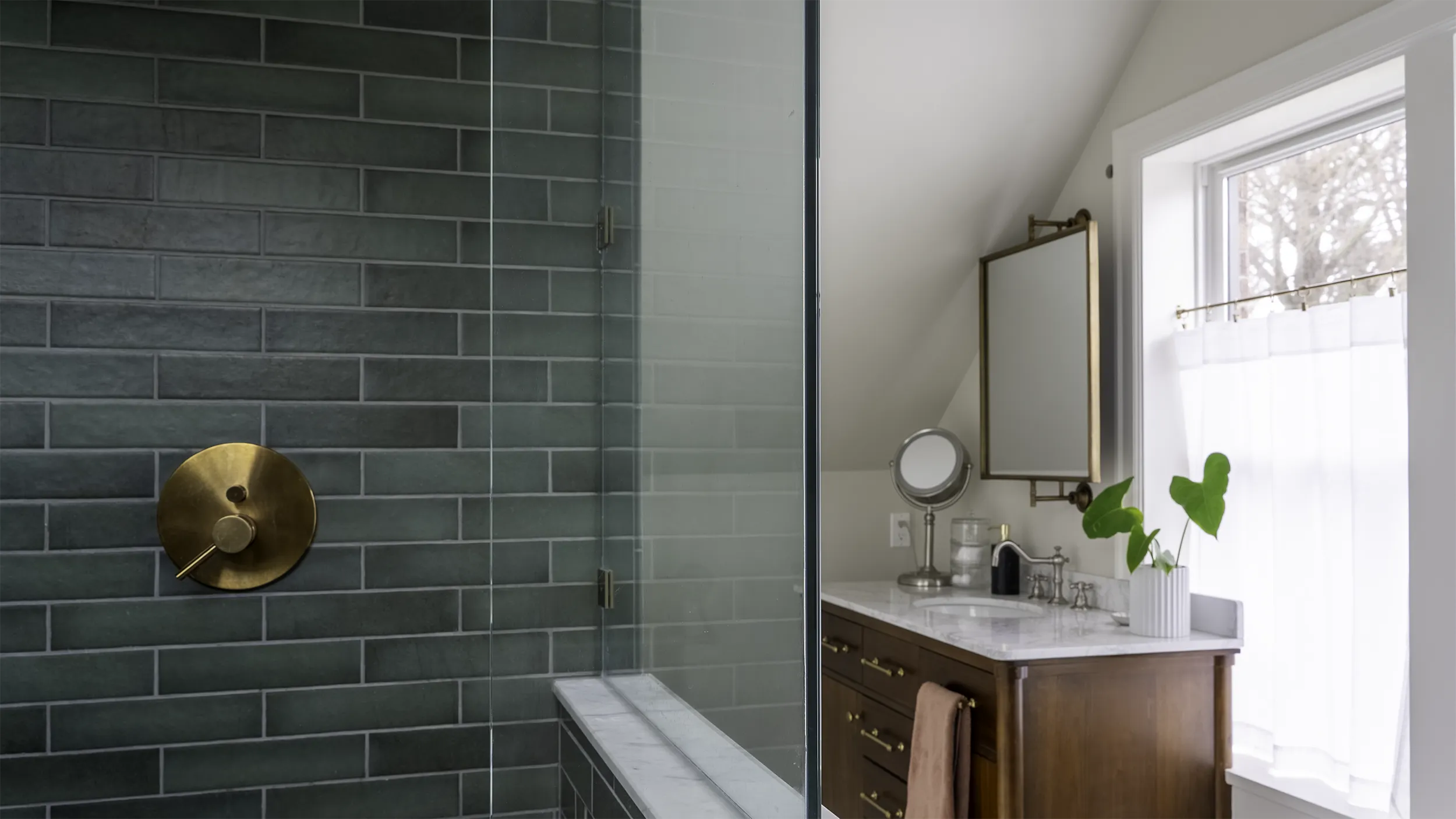 Primary bathroom remodel in Seattle's Maple Leaf neighborhood with deep green vertical-stack tile shower, brushed brass fixtures, glass enclosure, and vintage-style vanity
